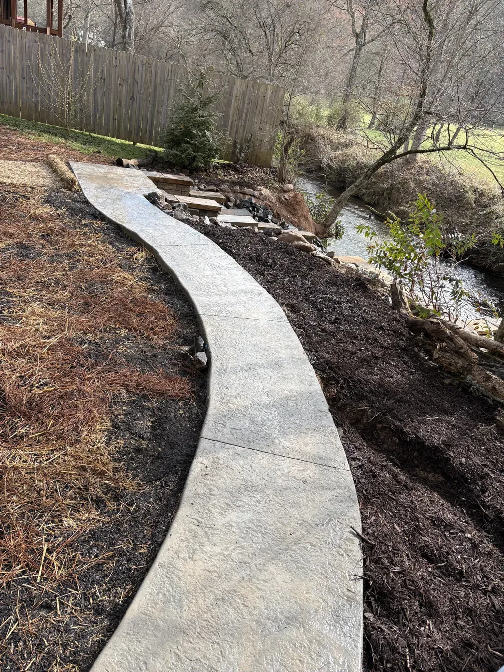 Curved stamped walkway beside a creek